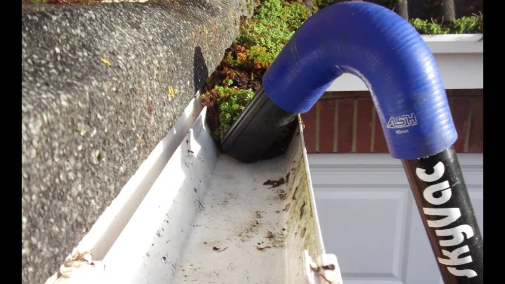 Close-up view of a partially restricted gutter showing debris accumulation and reduced water flow requiring professional inspection and maintenance.