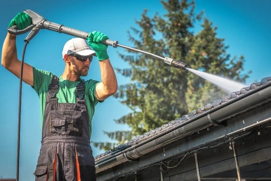 Technician pressure washing a residential roof and gutter system in Pennsauken, NJ